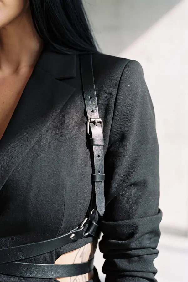 detail: Black blazer with built-in leather straps and wide-leg trousers