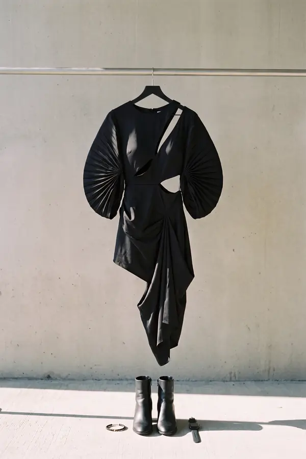 still life: Black satin cut-out dress with pleated fan sleeves