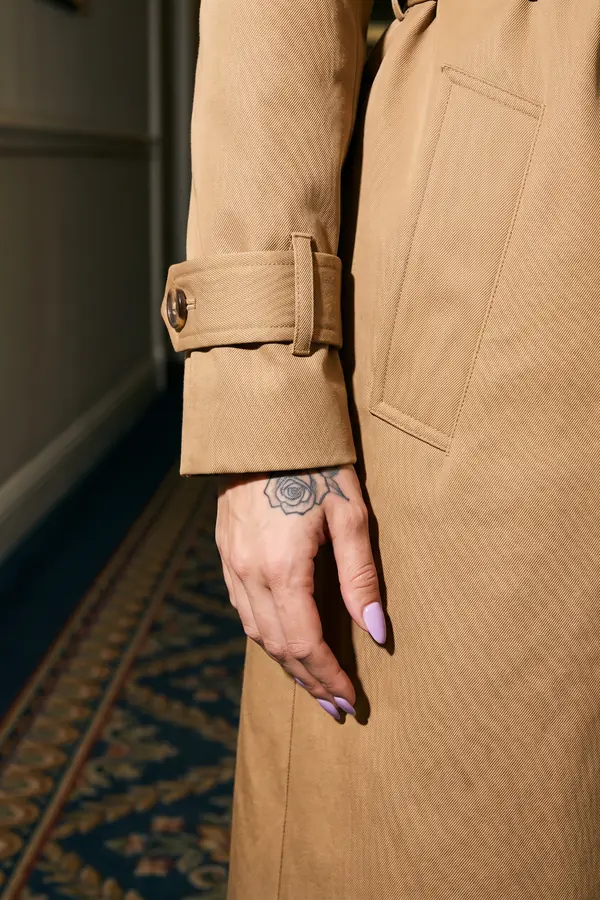 detail: Camel cotton trench coat worn closed and belted