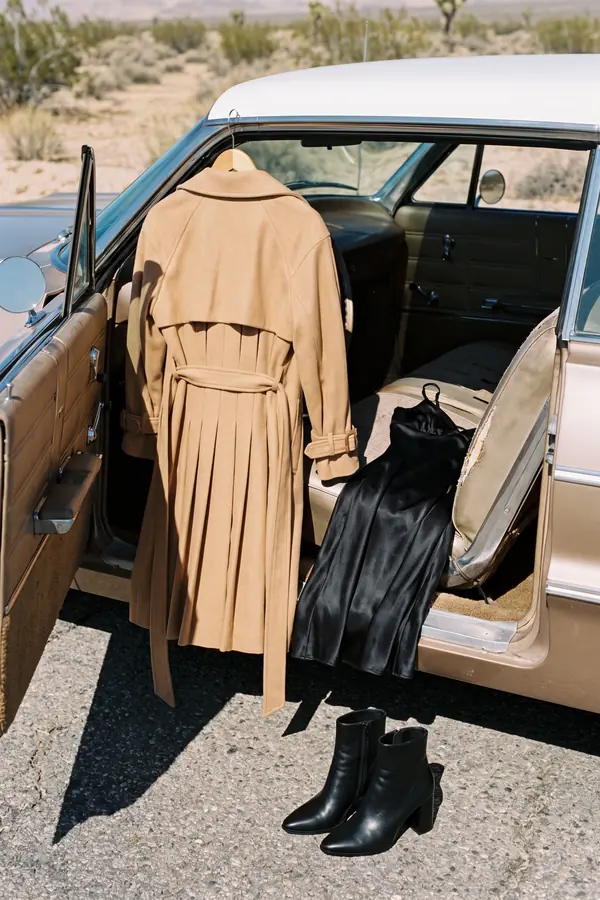 still life: Camel trench with a pleated back over a black slip dress