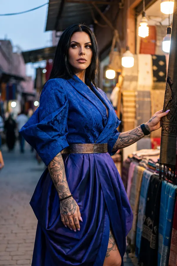 Woman in a cobalt brocade kimono top with a bronze belt and draped indigo satin skirt at a night market stall
