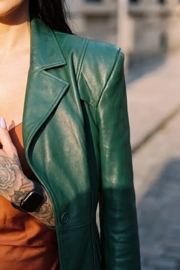 Woman walking on a cobbled street in a forest green leather blazer over a rust satin slip dress and chunky black boots