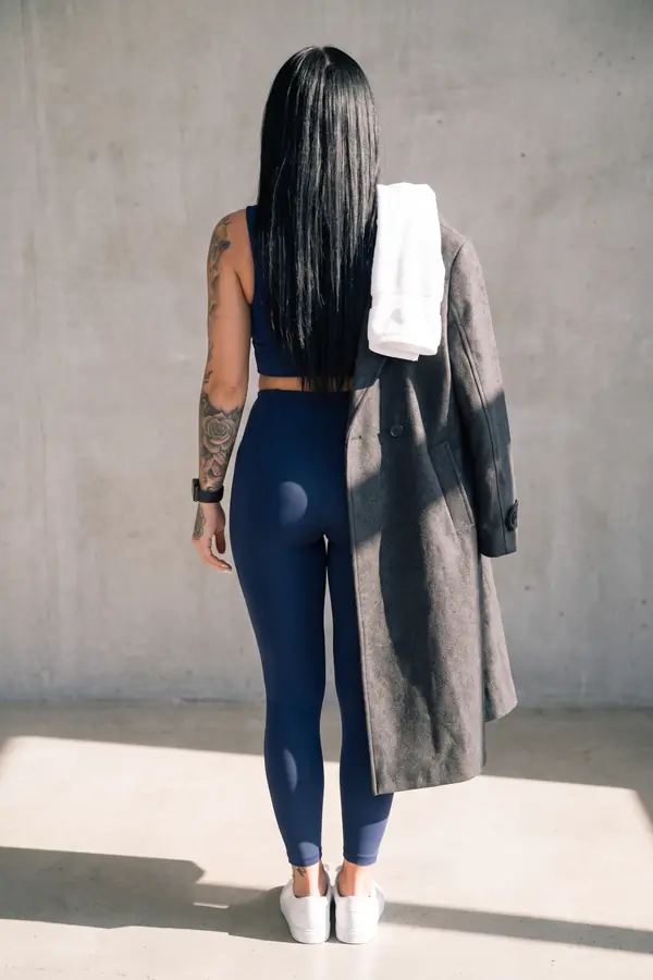 back & profile: Long charcoal wool coat over a navy sports top and leggings