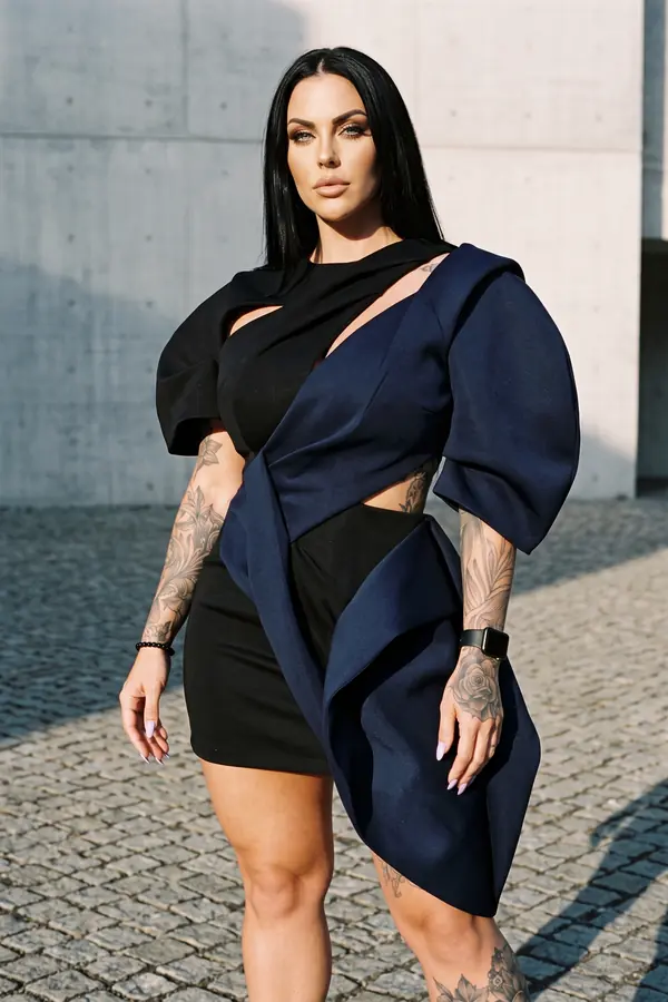 Woman in a black and navy colour-blocked mini dress with a balloon sleeve and cut-outs on a cobbled square