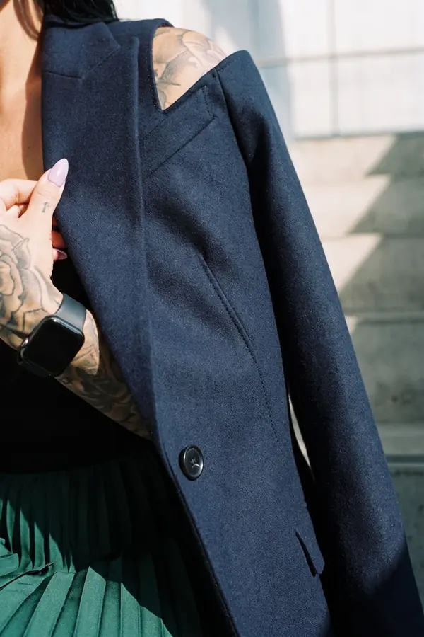 detail: Navy cut-out shoulder blazer with an emerald pleated skirt