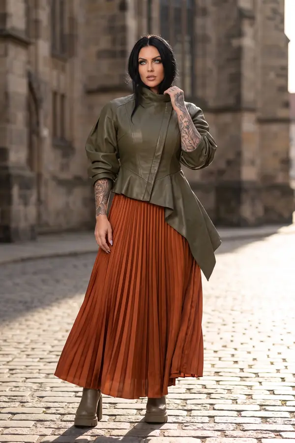 Woman in an olive leather peplum jacket, rust pleated satin maxi skirt and lug-sole boots on a cobbled street
