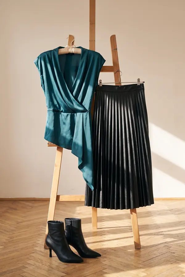 still life: Teal satin draped top with a pleated leather midi skirt