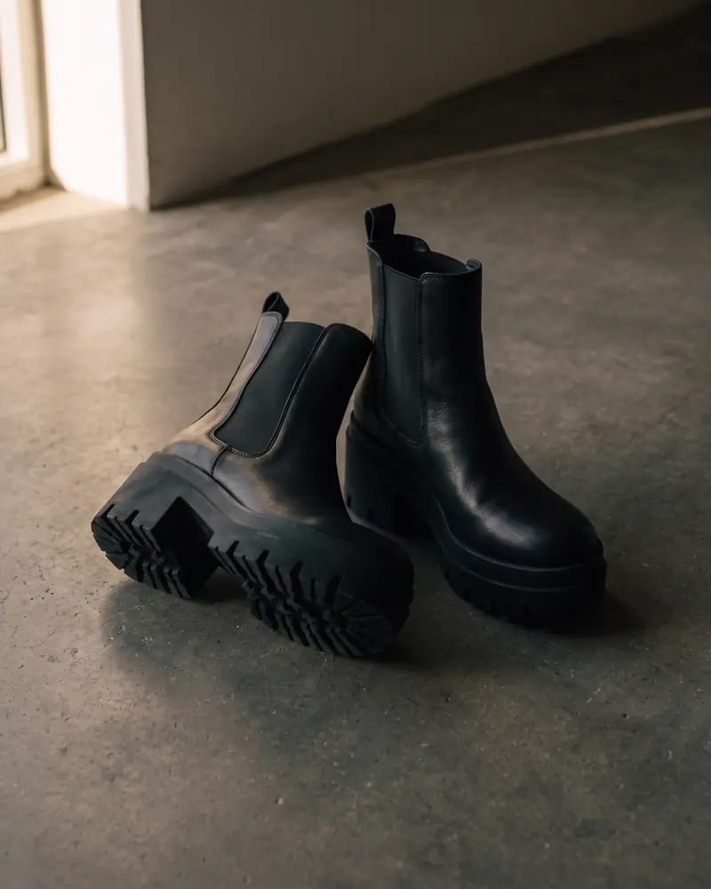 black leather lug-sole chelsea boots, a generated still life